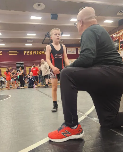 Coach Combs giving advice to wrestler during a match near Tempe, AZ